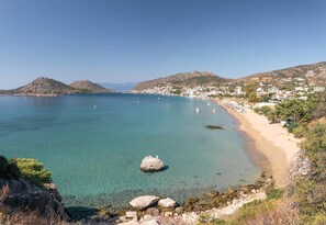 A coastal town with clear blue waters, a sandy beach, and rocky outcrops. - Psili Ammos (Nafplio)