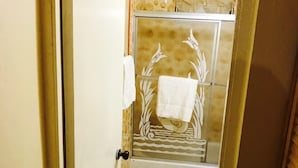 Un baño con ducha, inodoro y perchero para toallas.
