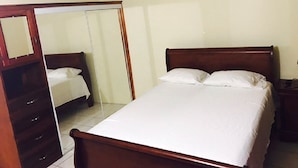Un dormitorio con una cama de madera, un aparador y un espejo de cuerpo entero.