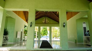 A covered outdoor area with a black mat leading to a beach view, featuring a wooden ceiling and green walls. - Seas the Day Sanctuary Little Bay (Negril)