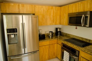 A kitchen with stainless steel appliances, wooden cabinets, granite countertops, and a built-in microwave.