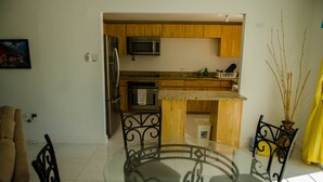 A modern kitchen with wooden cabinets, stainless steel appliances, and a granite countertop. - Seas the Day Sanctuary Little Bay (Negril)