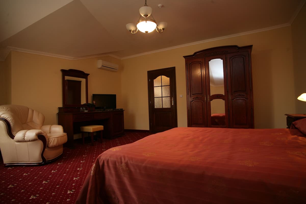 Habitación de hotel con una cama grande, un escritorio, una silla, un armario y una lámpara en el techo.