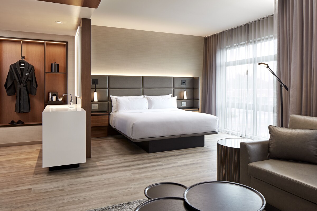 Une chambre d’hôtel moderne équipée d’un lit, d’un canapé, d’un bureau et d’un dressing.