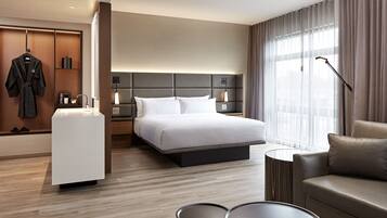 Ein modernes Hotelzimmer mit Bett, einer Sitzecke, einem Schreibtisch und einem begehbaren Kleiderschrank.