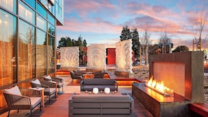 An outdoor seating area with a fire feature, modern furniture, and a view of the cityscape.