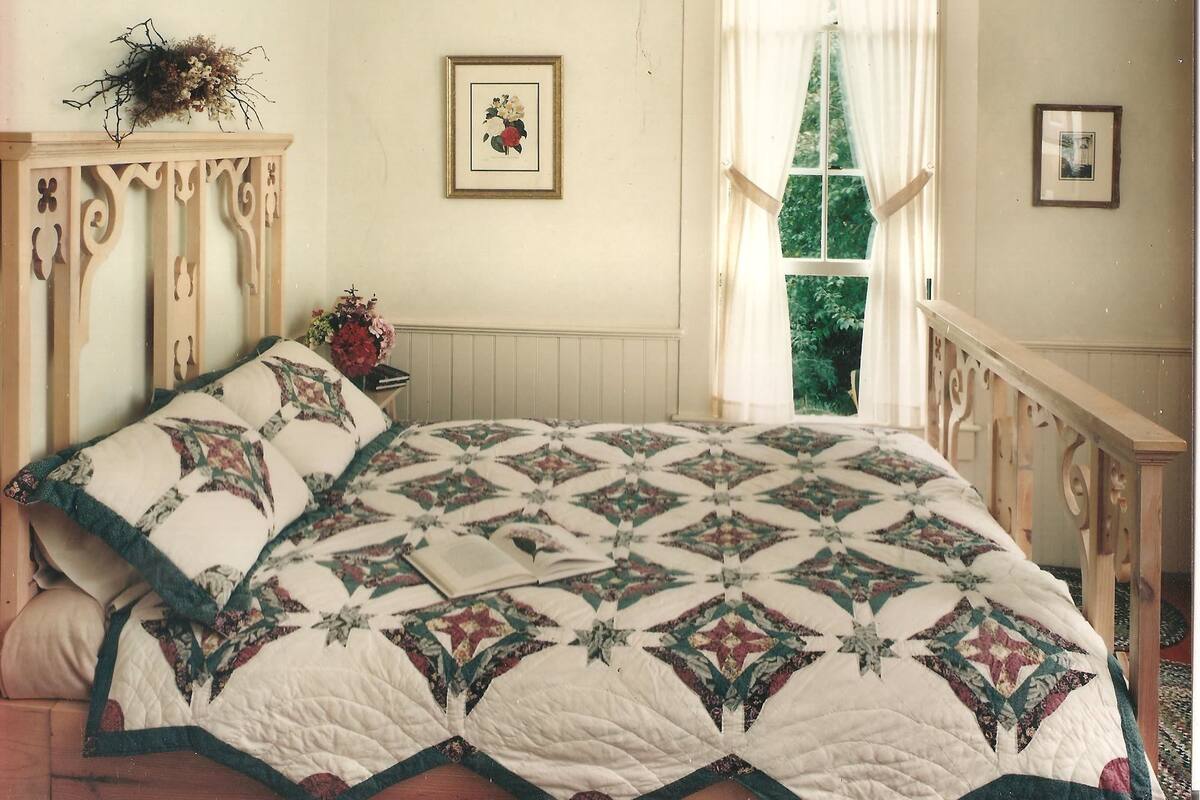 A bedroom with a large bed, a window with curtains, a wooden dresser, and a framed picture on the wall.