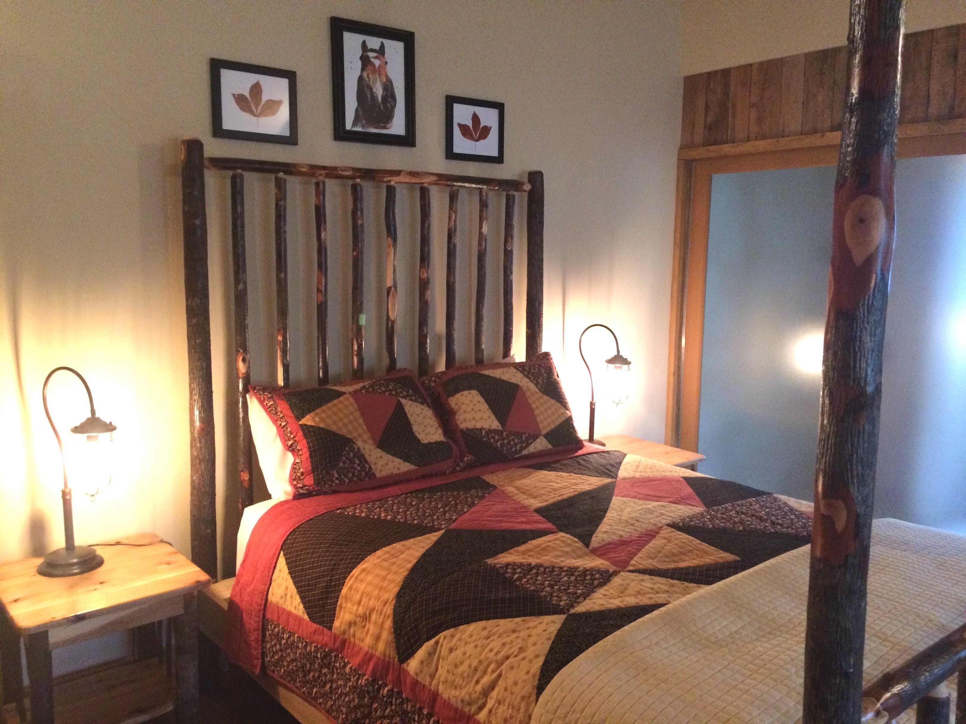 A bed with a quilt, a wooden headboard, and framed pictures on the wall.