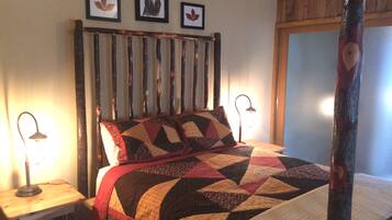 A bed with a quilt, a wooden headboard, and framed pictures on the wall.