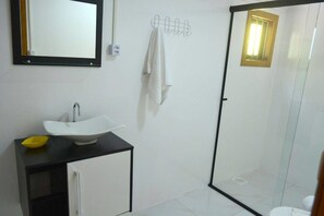 A bathroom with a white sink, black cabinet, and a glass shower enclosure. - Locar-in Gramado Residencial Centro Bem Estar (Gramado)