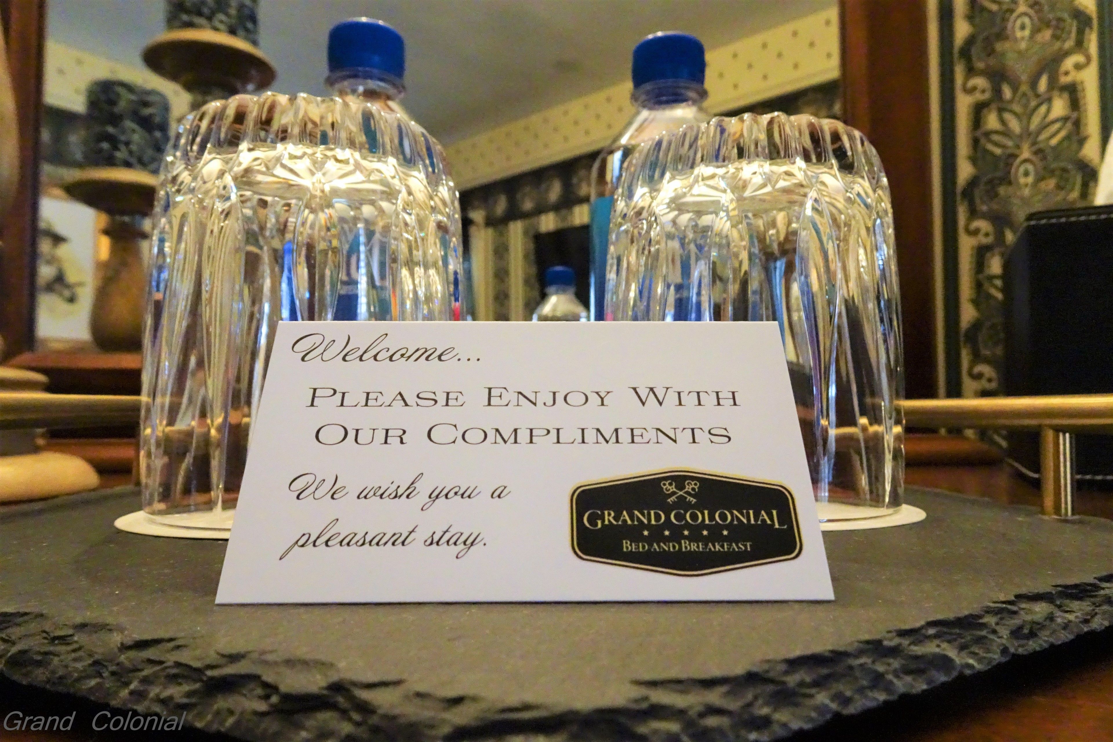 A welcome sign with a message and a logo for Grand Colonial Bed and Breakfast.