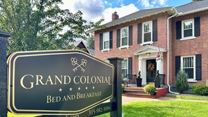 Une enseigne indiquant le « Grand Colonial Bed and Breakfast », avec un bâtiment en briques en arrière-plan.