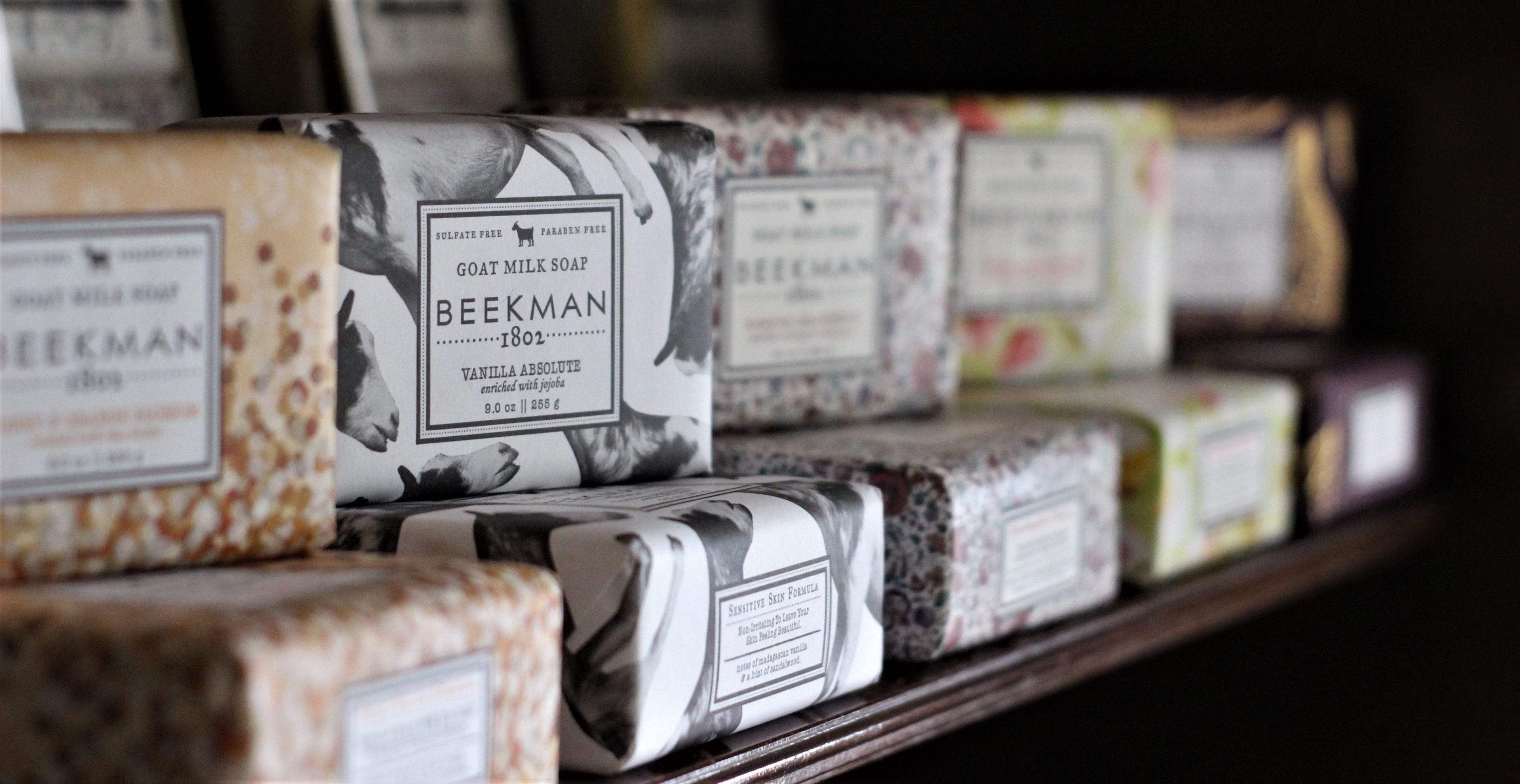 A shelf with various packaged soaps, including brands like Beekman and Goat Milk Soap.