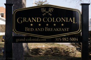 Une enseigne pour le Grand Colonial Bed and Breakfast, avec l’adresse du site web et le numéro de téléphone.