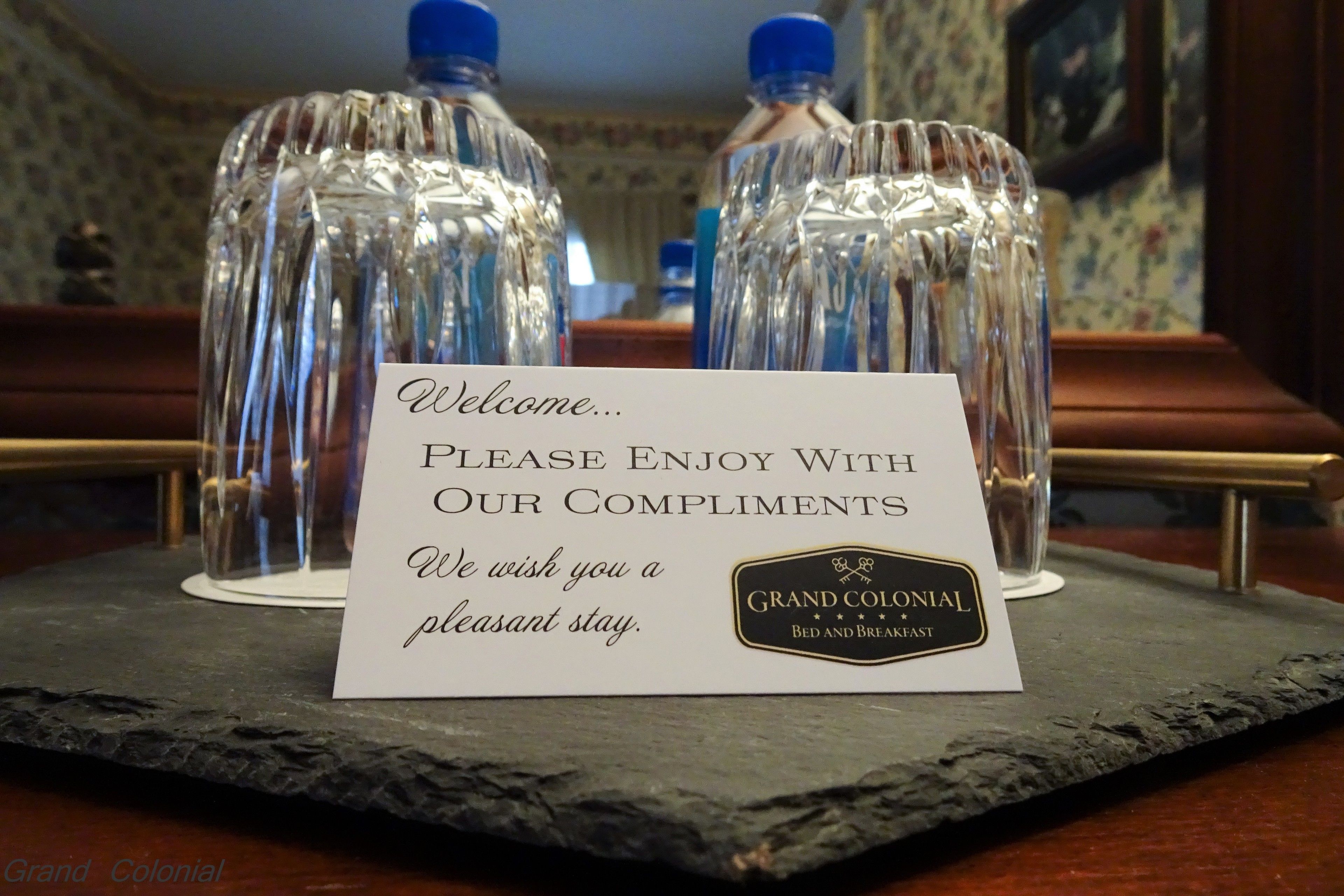 A welcome sign with a message and a logo for Grand Colonial Bed and Breakfast.