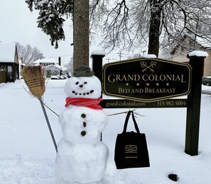 A snowman with a broom and a bag in front of a sign for Grand Colonial Bed and Breakfast. - Grand Colonial B&B (Herkimer)