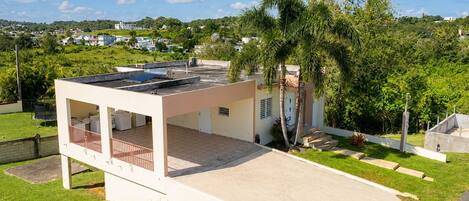 A modern house with a flat roof, a covered patio, and a paved driveway.