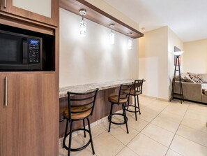A kitchen with a microwave, a bar counter, and three stools. - Casa vacacional en Arenales Isabela (Isabela)