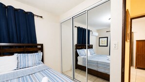 Ett hotellrum med en säng, en spegel och en dörr.