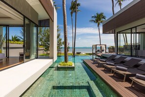 A modern pool area with lounge chairs, a clear pool, and a view of the ocean. - Villa Anar (Koh Samui)