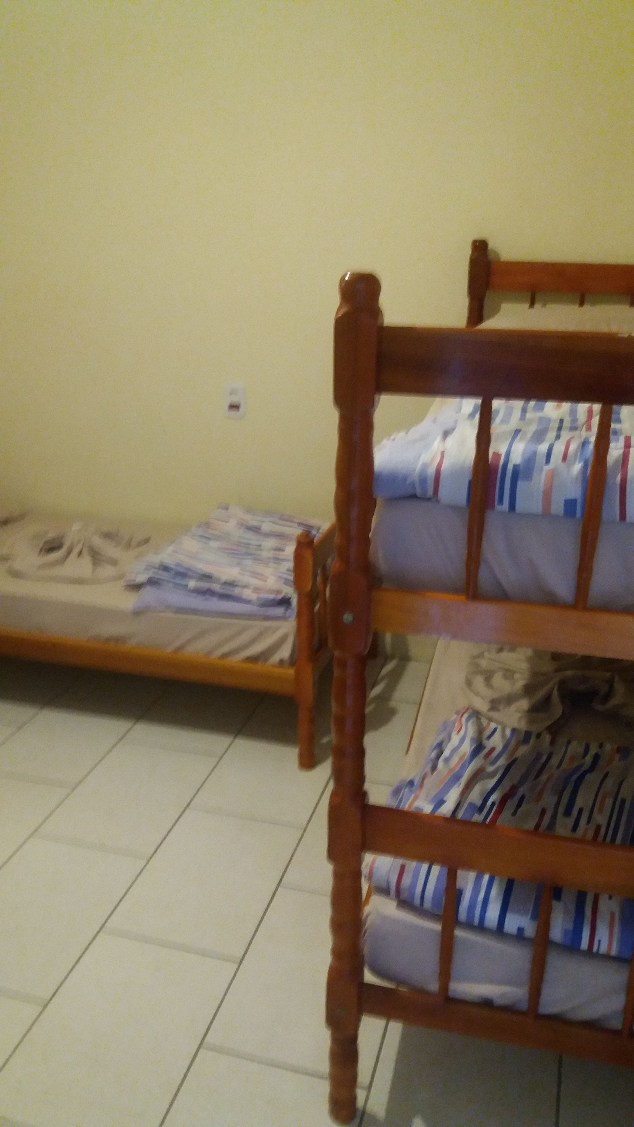 Uma cama de beliche com estrutura de madeira e colchão com roupa de cama listrada.