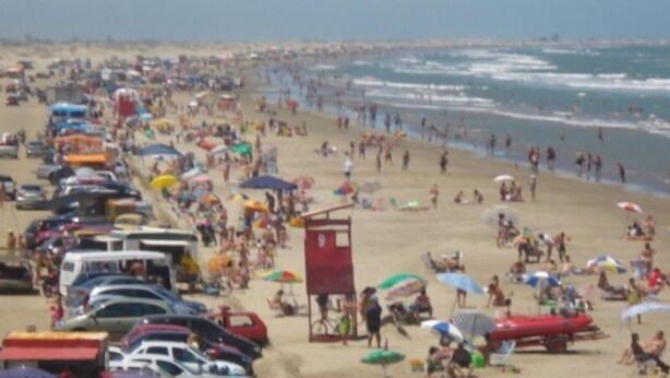 Une plage bondée, avec de nombreux parasols et des vacanciers.