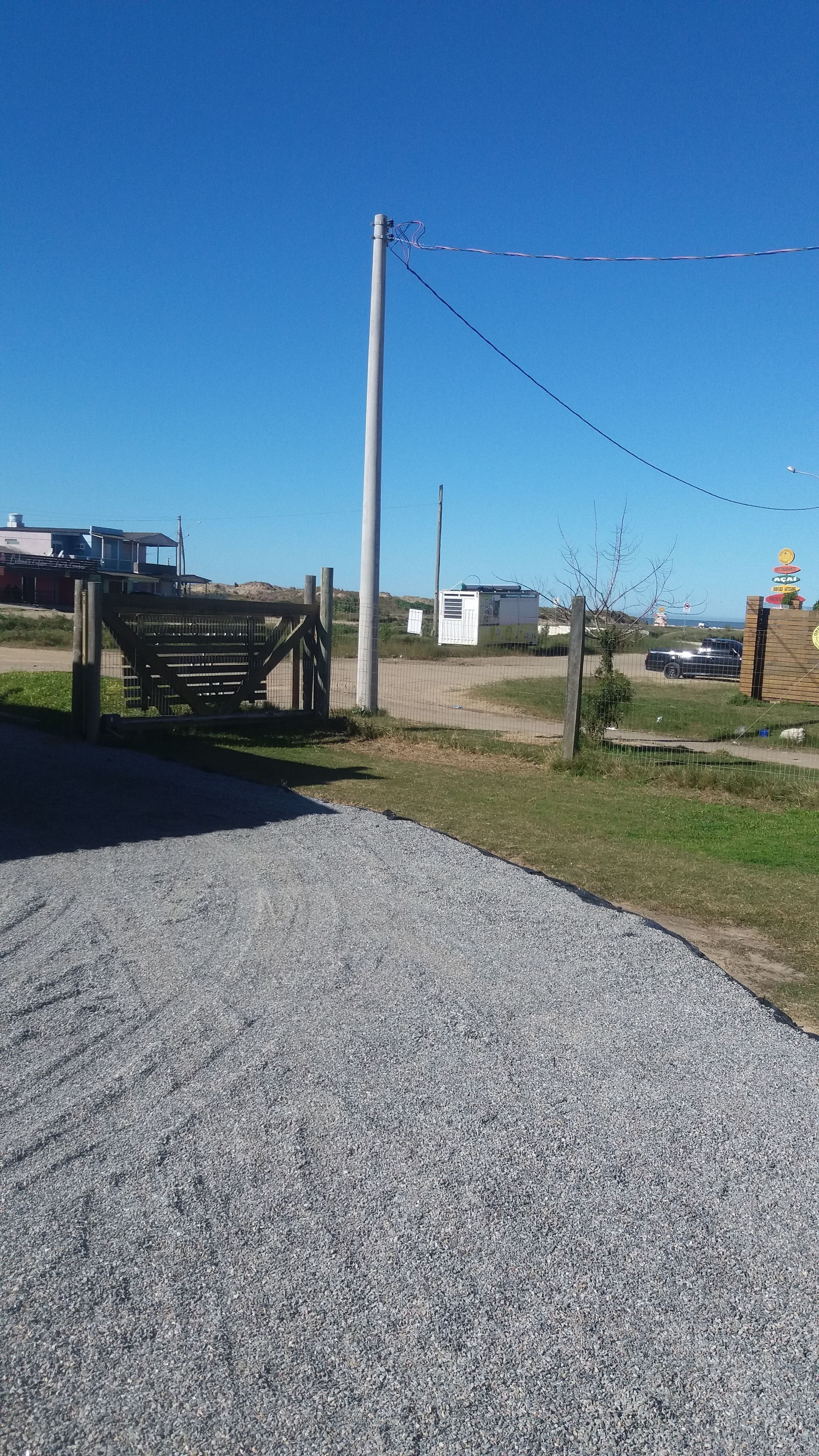Un sendero de grava que conduce a una entrada con portón y un banco.