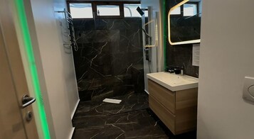 Un baño moderno con pared de ducha de mármol, tocador de madera y espejo.