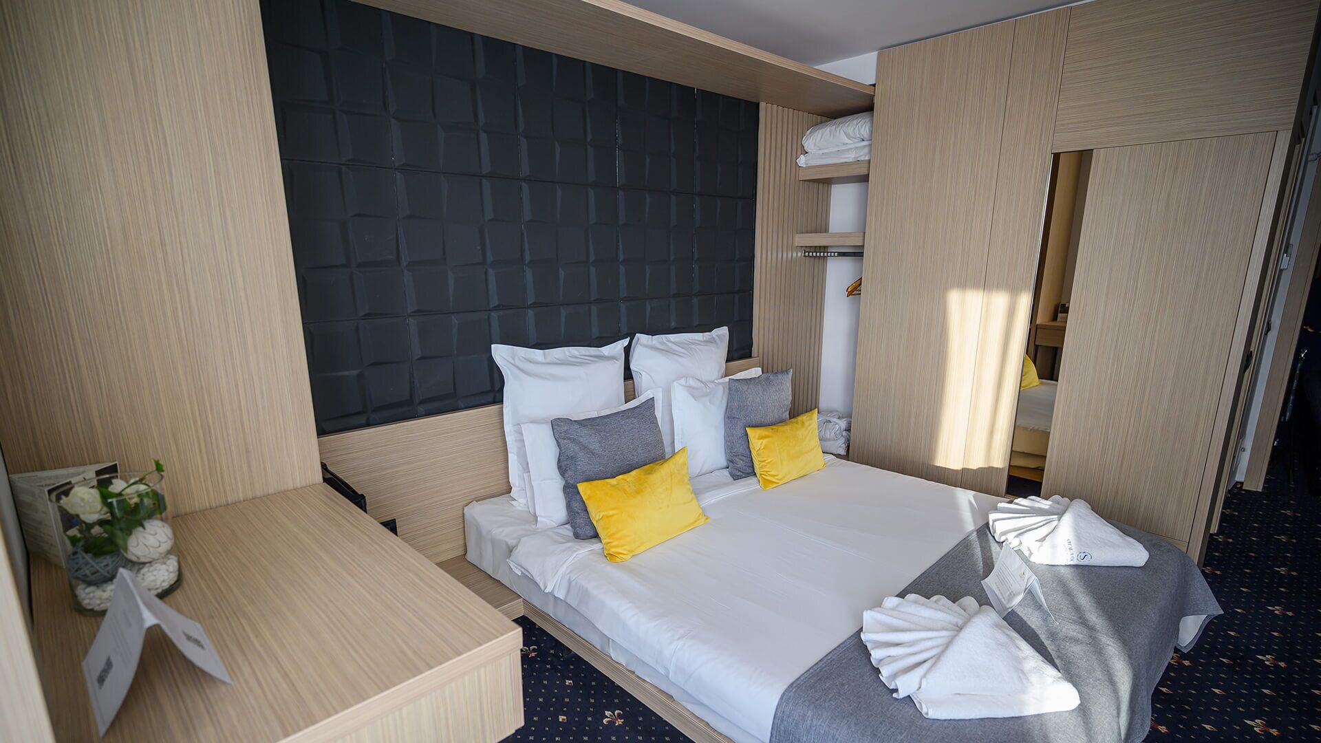 Ett modernt hotellrum med en stor säng, ett nattduksbord och en sänggavel.