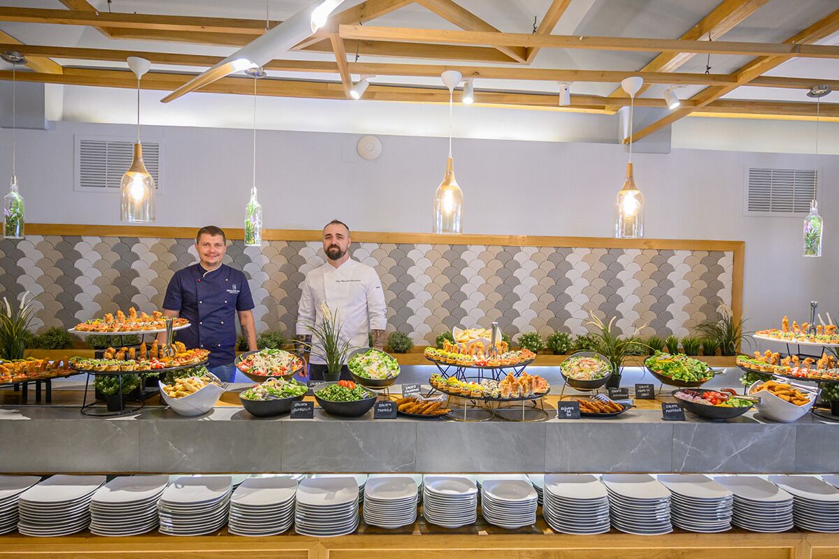 Un aparador de buffet amb diversos plats i un cuiner darrere del taulell.