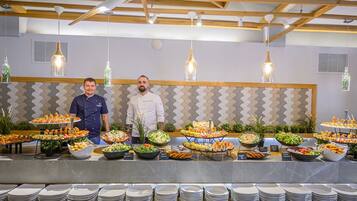 Un aparador de buffet amb diversos plats i un cuiner darrere del taulell.