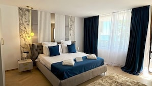 A modern bedroom with a large bed, a nightstand, a marble wall, and a view of the outdoors. - Aqvatonic Balneo Spa - Steaua de Mare (Eforie)