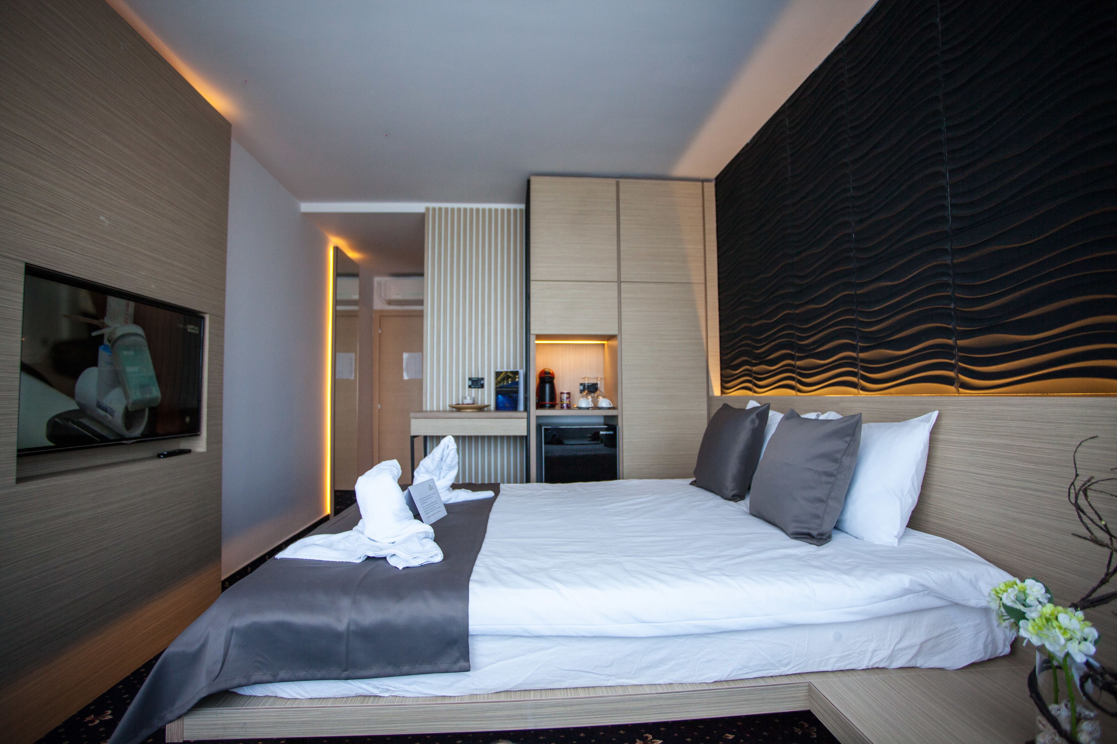 Et moderne hotelværelse med en stor seng, et skrivebord og et spejl.