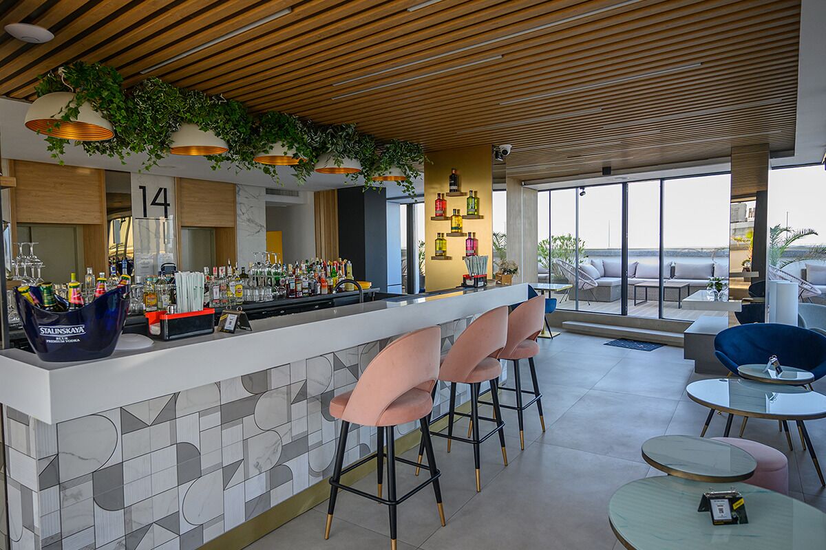 A modern bar area with a wooden ceiling, bar stools, and a view of the outdoors.