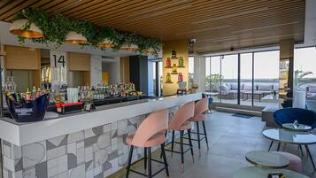 A modern bar area with a wooden ceiling, bar stools, and a view of the outdoors.