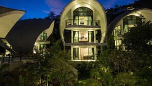 Un bâtiment moderne à plusieurs étages, doté d’une toiture incurvée, de grandes fenêtres et d’un balcon.