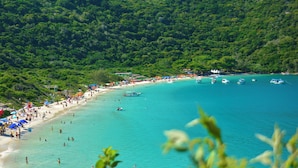 Une plage bordée d’une eau turquoise et limpide, entourée de collines verdoyantes.