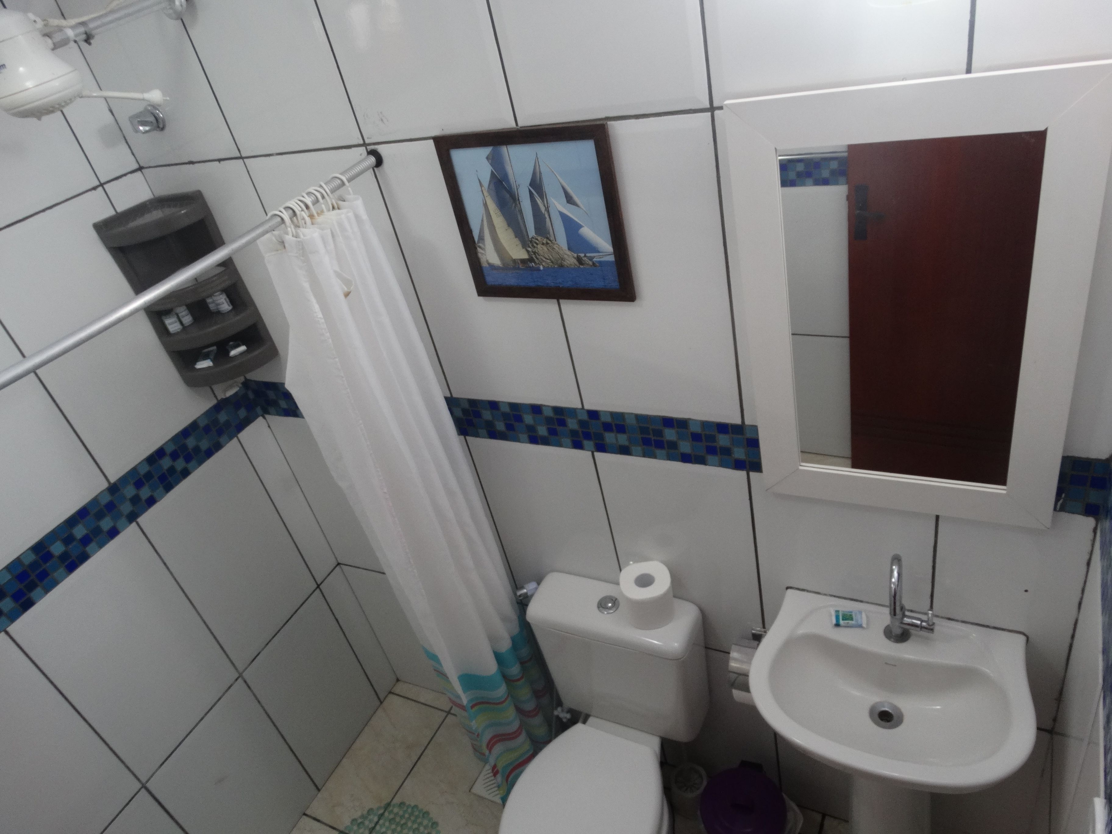 Un bagno con WC, lavandino e tenda della doccia.