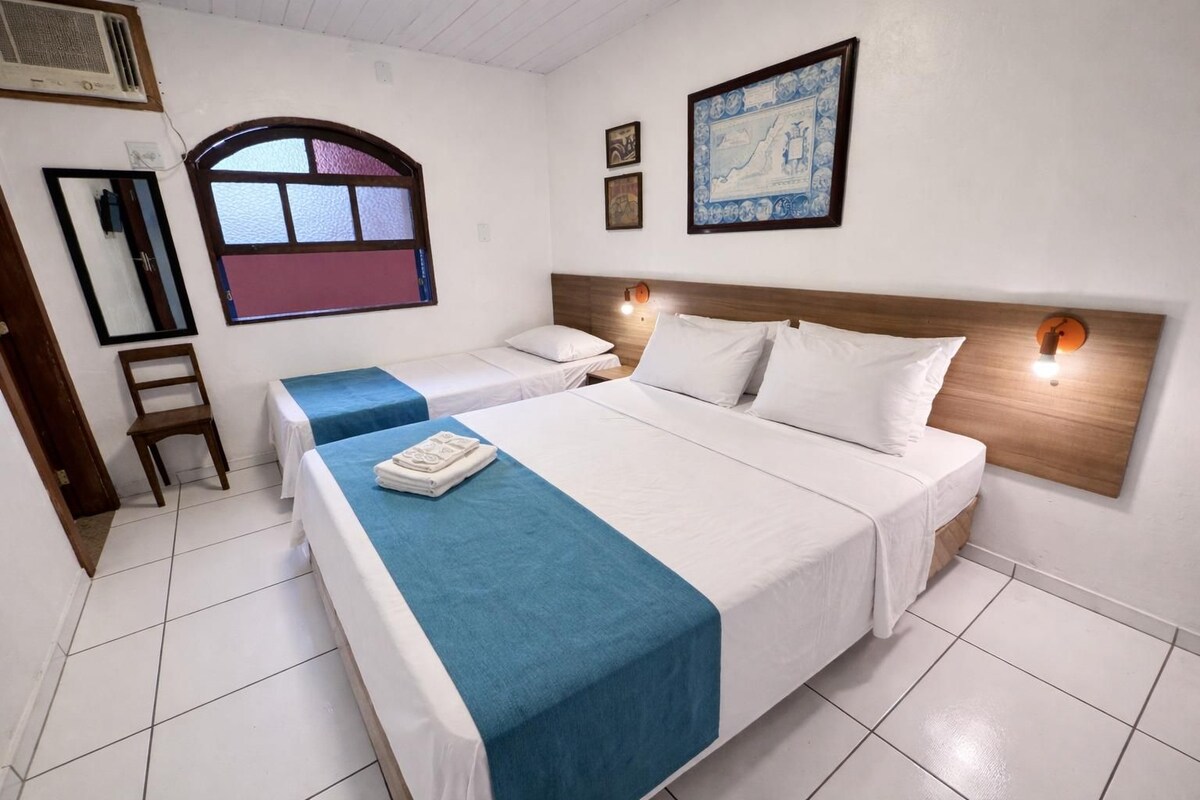 Una habitación de hotel con dos camas, un cabecero de madera, una ventana con vistas y una lámpara de pared.