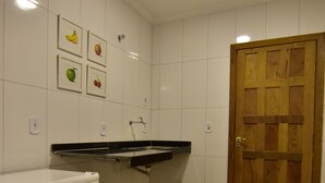 Une cuisine de taille réduite avec des carreaux blancs, une porte en bois et un réfrigérateur blanc.