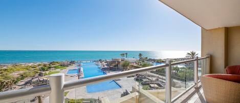 A balcony with a view of a swimming pool and the ocean.