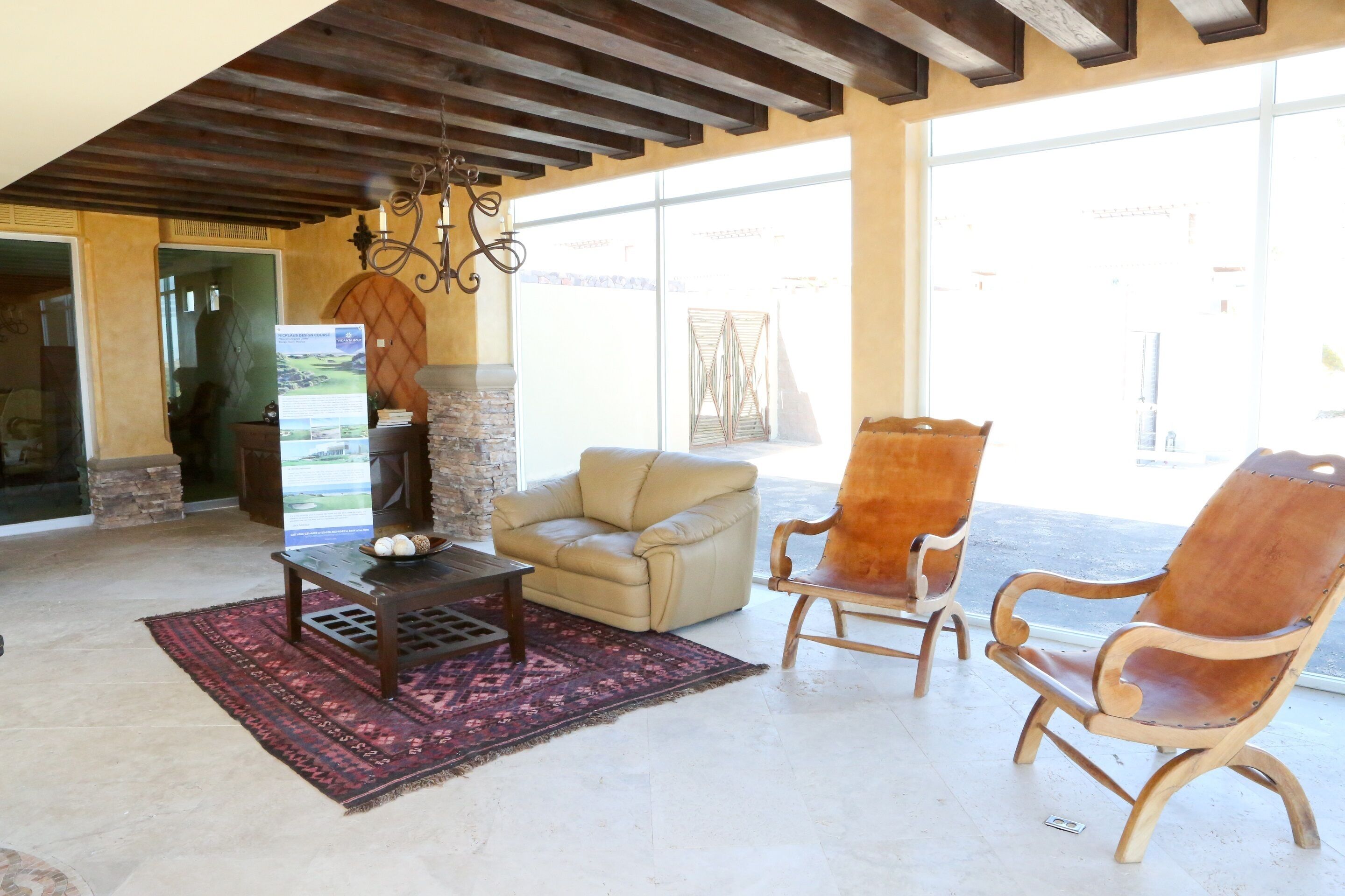 A spacious living area with a stone fireplace, a beige leather sofa, and a wooden armchair.