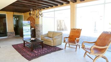 A spacious living area with a stone fireplace, a beige leather sofa, and a wooden armchair.
