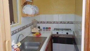 A compact kitchen with a sink, a stove, and a dish rack. - Casa Armando y Mercy (Havana)