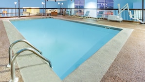An indoor swimming pool with a clear blue water, a metal ladder, and a railing. - Days Inn & Suites Grand Rapids Near Downtown (Grand Rapids)