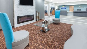 A hotel lobby with a fireplace, a reception desk, and a seating area with a patterned carpet. - Days Inn & Suites Grand Rapids Near Downtown (Grand Rapids)