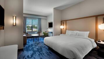 Een hotelkamer met een groot bed, een bureau, een stoel en een televisie.