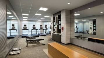 A modern fitness center with treadmills, a bench, and a mirrored wall.
