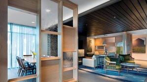 A modern interior with a dining area, a living room with a sofa and armchairs, and a wooden ceiling. - Fairfield Inn & Suites by Marriott Shelby (Shelby)