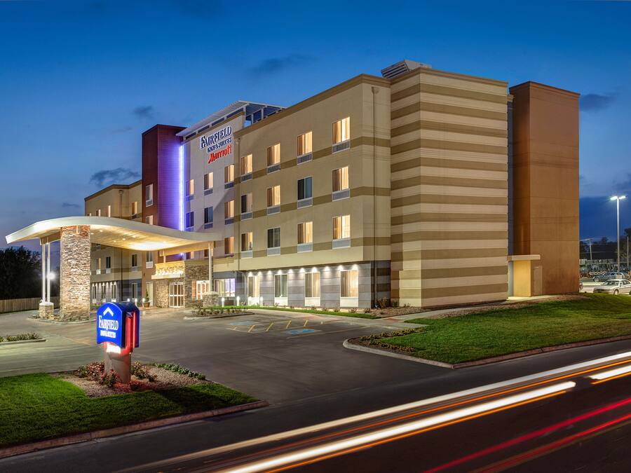 Un hôtel à plusieurs étages, doté d’une entrée imposante, d’une façade bien éclairée et d’un parking.